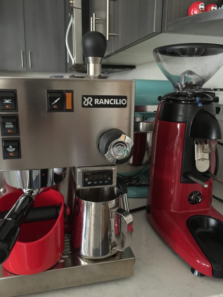 A Rancilio Silvia coffee machine and a coffee pot on a kitchen counter.