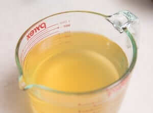 A measuring cup filled with yellow dashi broth.