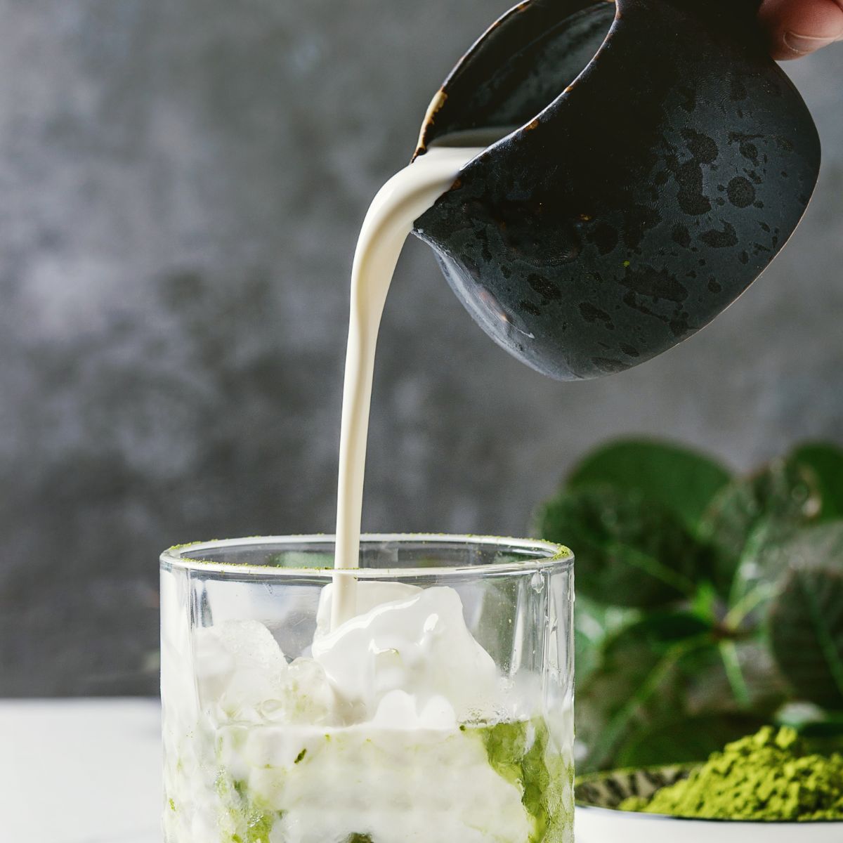 Milk added in a glass of matcha powder