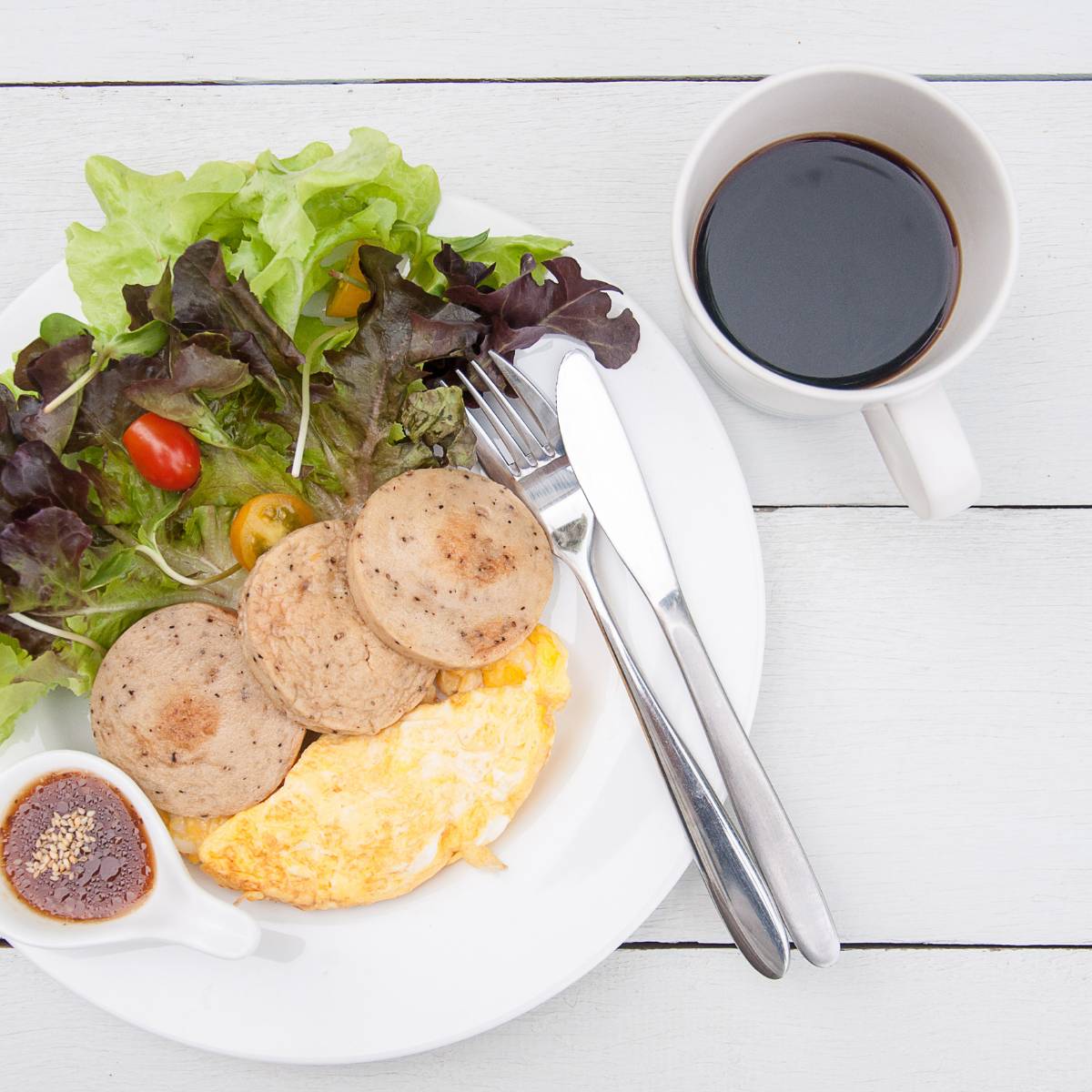 A plate of salad and meats with japanese salad dressing on the side