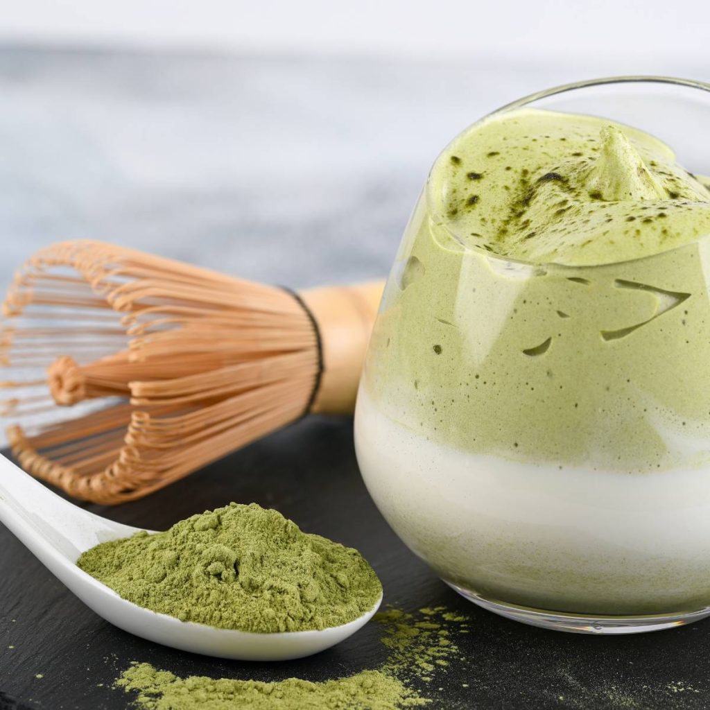 Glass of matcha milk tea with matcha powder on the side