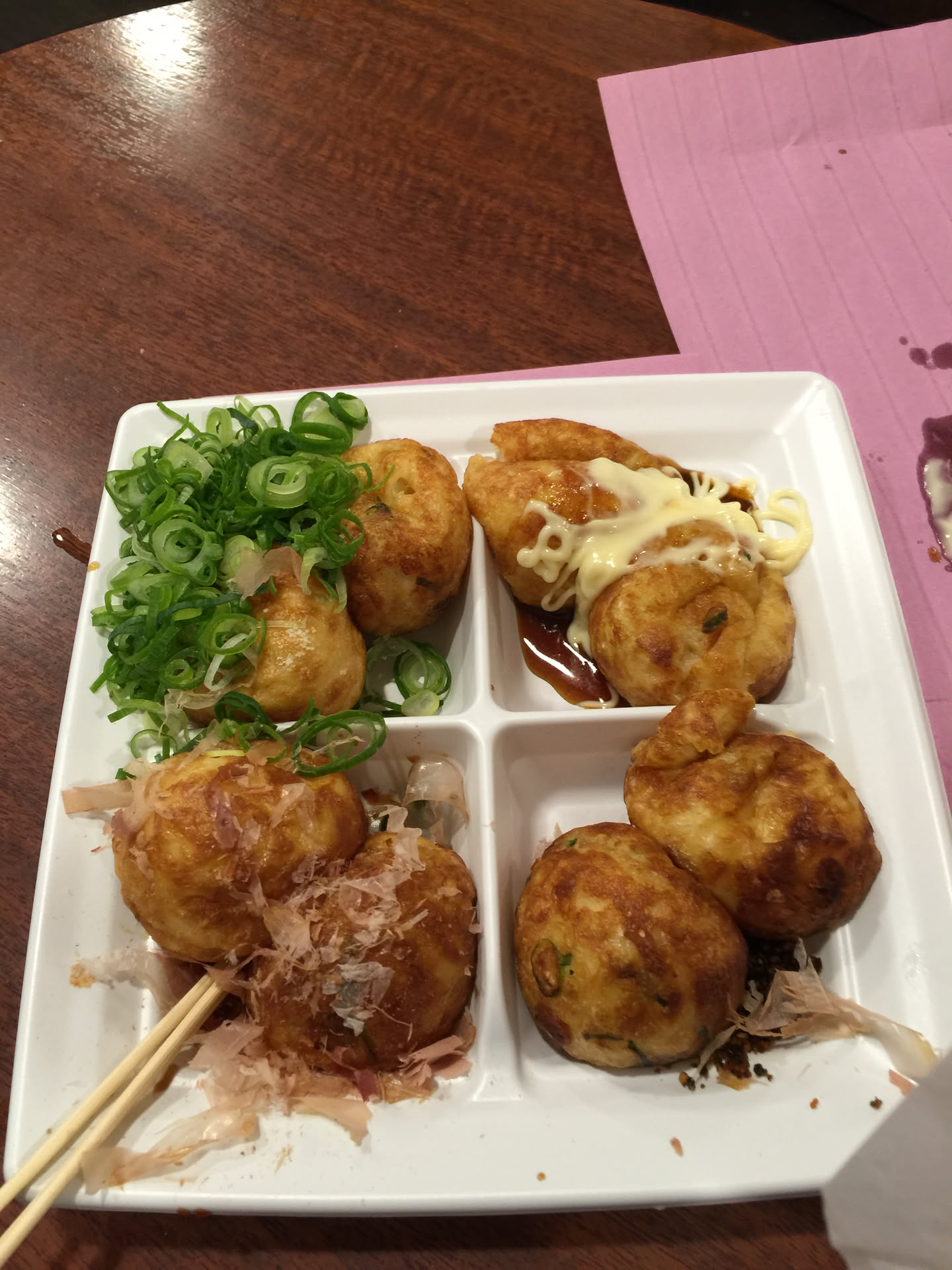 Four varieties of freshly made round takoyaki in a compartment tray