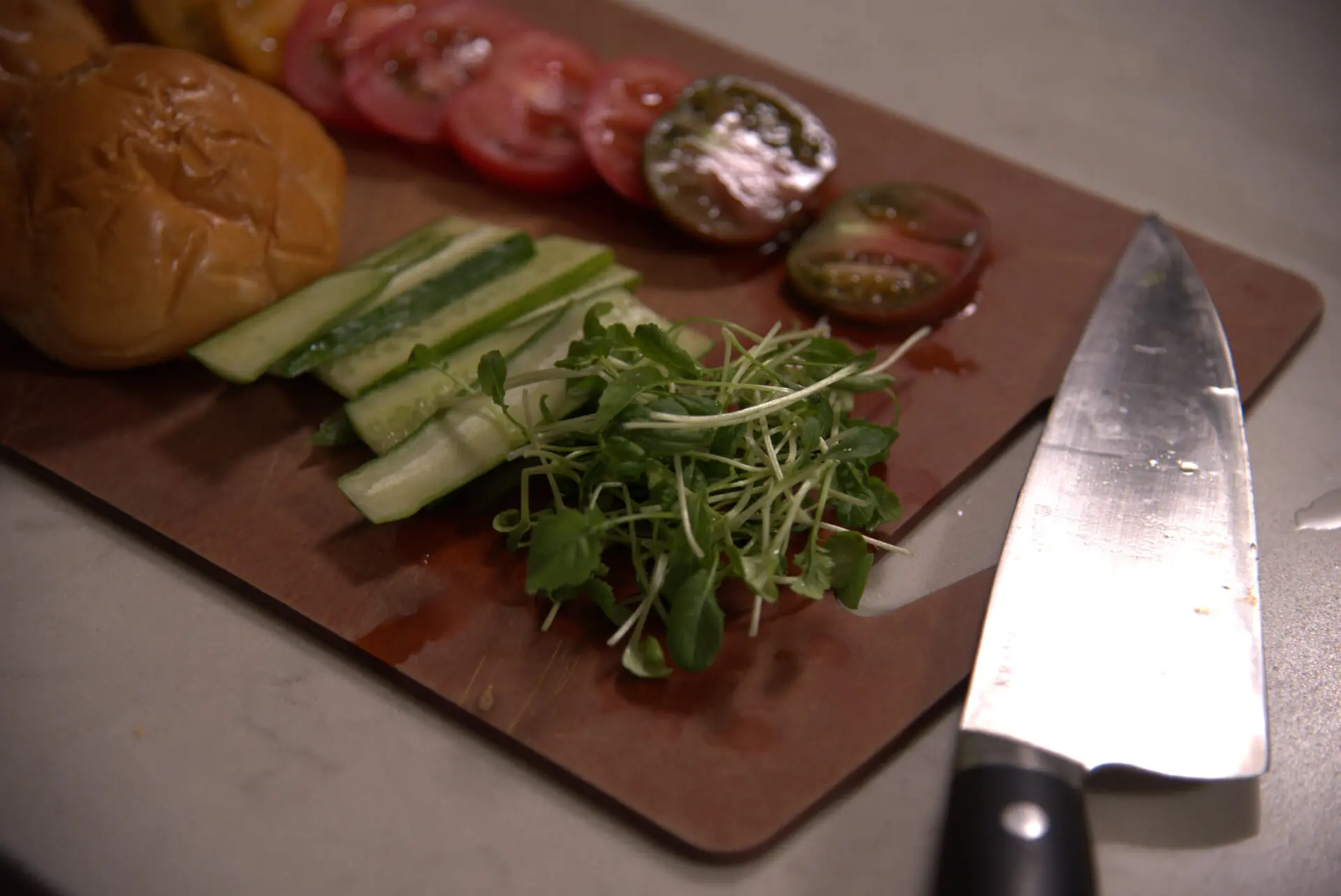 Sharp kitchen knife beside cleanly sliced tomatoes on a cutting board