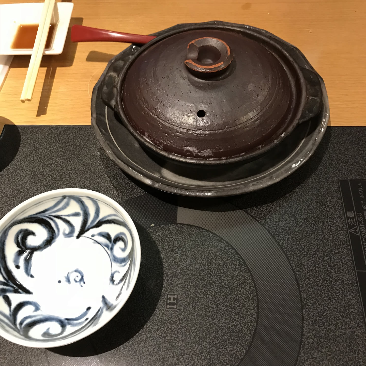 Clay donabe pot with lid on a Japanese cooktop