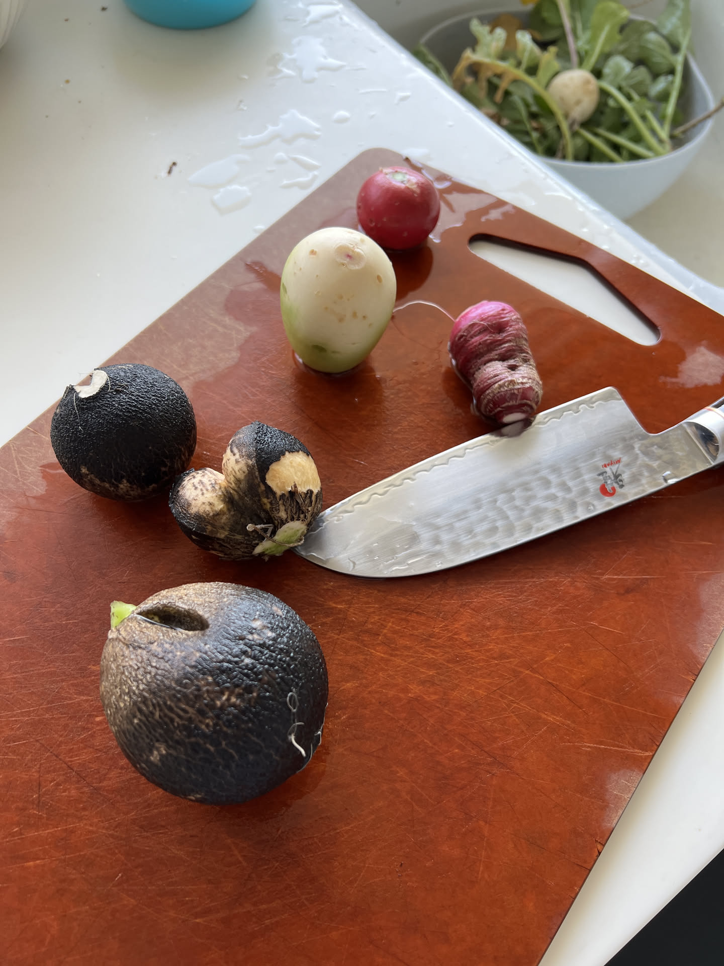 Hammered santoku knife with radishes on a cutting board